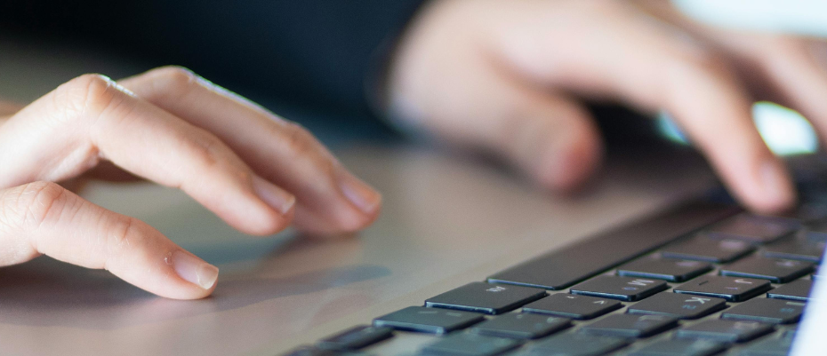 Hands typing on a laptop to represent using AI in marketing