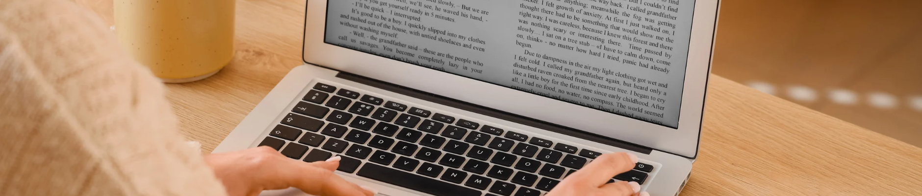 Person typing on laptop with paragraph text on screen.
